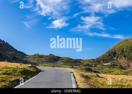 Route de montagne courbant à travers les pentes d'herbe sous le ciel bleu à Vinadio, Piémont, Italie Banque D'Images