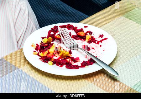 Assiette de restes de salade avec fourchette sur une nappe colorée à motifs Banque D'Images