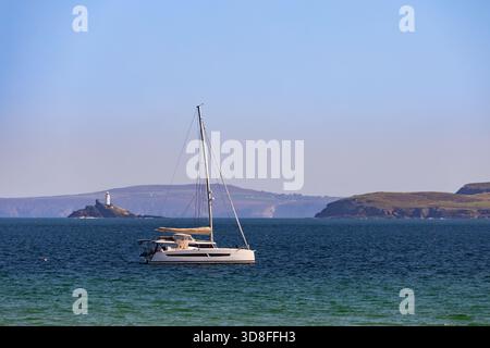 Un voilier est ancré dans la baie de St Ives, Cornouailles, Angleterre, Royaume-Uni, Europe, avec vue sur le phare de Godrevy Banque D'Images