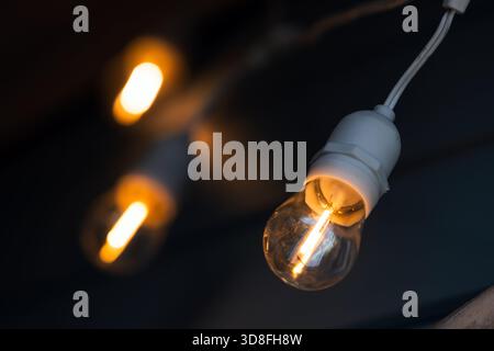 Les ampoules Edison douces et chaudes accrochent dans un espace sombre, offrant une lueur chaleureuse et ambiante qui améliore la décoration intérieure et les décors d'ambiance pour la photographie et la vidéo pr Banque D'Images