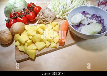 Ingrédients pour un ragoût à base de pommes de terre et de chou avec des oignons, du céleri, des tomates et des carottes, partiellement haché sur un comptoir de cuisine, espace de copie, Banque D'Images