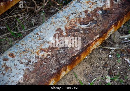 Texture de poutre métallique industrielle fortement rouillée avec peinture pelable sur la saleté et l'herbe Banque D'Images