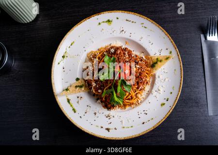 Spaghetti bolognaise avec sauce à la viande, fromage, herbes et pain grillé sur une assiette en céramique. Réglage de table rustique. Banque D'Images