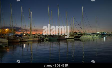 Les voiliers reposent calmement à Mikrolimano tandis que le coucher du soleil peint la marina dans des tons chauds. Banque D'Images