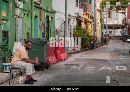 Gars assis sur une chaise dans une ruelle à Kampong Glam, Singapour Banque D'Images