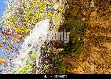 Une superbe cascade descend les falaises rocheuses, entourées d'une végétation luxuriante. L'eau cristalline coule avec puissance et grâce, créant un serein Banque D'Images