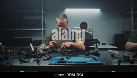 Professionnels adultes dans la construction d'installations modernes et le raffinage de véhicules aériens sans pilote avancés travaillant. Concept de l'avenir de la technologie, affiner l'UAV, la robotique et l'ingénierie aérospatiale en action. Banque D'Images