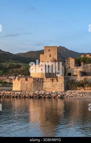 Le château royal historique de Collioure (Château Royal de Collioure) sur le front de mer, reflétant dans la mer Méditerranée au coucher du soleil Banque D'Images
