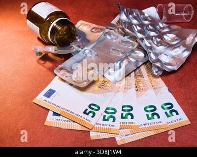 Coût de la médecine : pilules vides & euros - blisters vides de pilule, une bouteille de médicament, et 50 euros billets de banque sur fond rouge. Illustre l'augmentation de la Healthca Banque D'Images