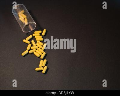 Bouteille de médecine et pilules jaunes - un coup de tête de nombreuses capsules jaune vif, potentiellement des médicaments sur ordonnance, dispersés d'une ouverture Banque D'Images
