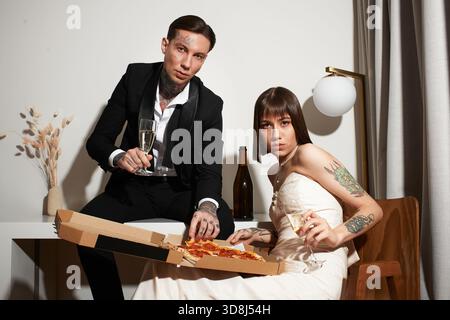 Un jeune couple profite d'une soirée agréable ensemble, partageant pizza et boissons dans leur chambre d'hôtel. Banque D'Images