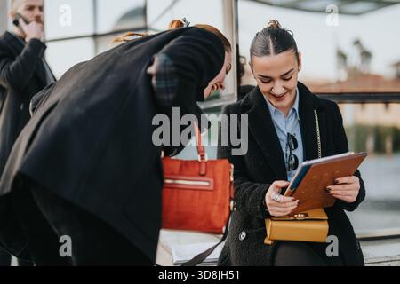 Deux jeunes collègues partagent un moment convivial à l’extérieur, examinant des documents ensemble pendant une pause Banque D'Images