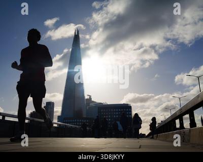 Coureur silhouette contre la ligne d'horizon en traversant le London Bridge dans le centre de Londres, avec le Shard en arrière-plan Banque D'Images