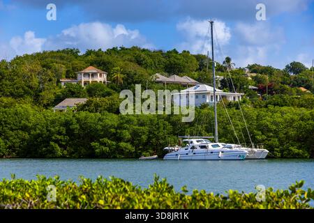 Antigua-et-Barbuda, Antilles, île d'Antigua. Port anglais, catamarans à l'ancre et villa de luxe Banque D'Images