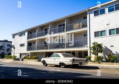 Voiture ancienne 1963 Ford Galaxie 500 garée dans un immeuble d'appartements de style dingbat à Los Angeles, avec des places de parking « soft story », architecture rétro Banque D'Images