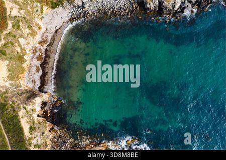Vue aérienne de la côte accidentée embrassant la paisible crique turquoise, où les falaises rencontrent la mer dans une symphonie de textures et de tons, fait Davi Banque D'Images
