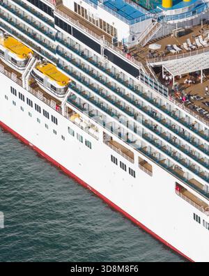 Vue aérienne du côté d'un vaste navire de croisière avec sa coque blanche, ses rangées de fenêtres et ses canots de sauvetage, contrastant avec la mer bleu profond, Trieste, Ita Banque D'Images