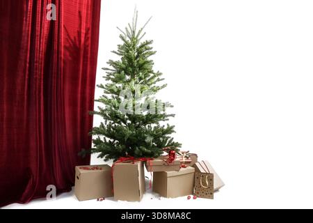 Arbre de Noël sans décorations, sous de nombreuses boîtes en carton pour les cadeaux prêts à être emballés, rideau rouge à gauche, côté droit contre un blanc Banque D'Images