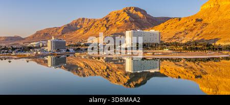 Vue aérienne des montagnes embrassées par le soleil embrasser les eaux sereines et réfléchissantes reflétant l'architecture de la ville dans une danse tranquille de lumière et d'ombre, T Banque D'Images