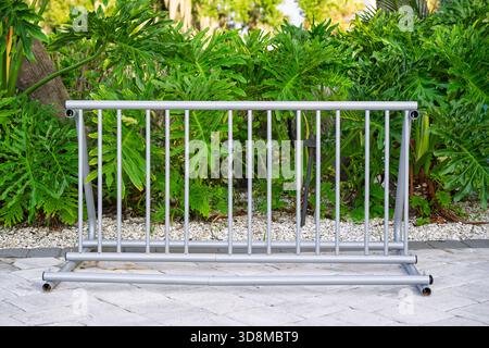 Un porte-vélos argenté se tient prêt sur des pavés de pierre lisses, encadrés par un mur luxuriant de végétation verte vibrante en arrière-plan. Banque D'Images