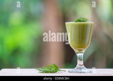 Smoothies verts frais d'avocat, banane, aneth et miel dans un gobelet en verre dans une table en bois, Thaïlande, gros plan Banque D'Images