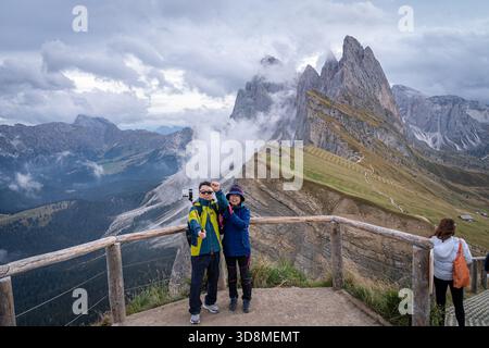 Couple asiatique prend un selfie devant Seceda Ridgeline dans les Dolomites. Italie. Banque D'Images