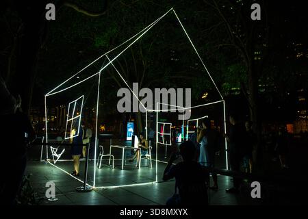 Sculpture lumineuse géométrique illuminée dans un parc urbain la nuit attire la foule pour la photographie de nuit Banque D'Images