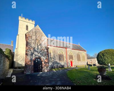 Église paroissiale en pierre historique avec clocher carré et fenêtres cintrées à Churston Ferrers, Devon, Angleterre, entourée de pierres tombales de cimetière Banque D'Images