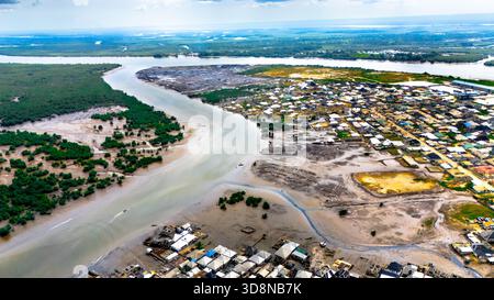 Vue aérienne du front de mer de Bundu avec une rivière serpentant à travers une végétation dense et des établissements urbains sous un vaste ciel, Port Harcourt, Rivières, Niger Banque D'Images