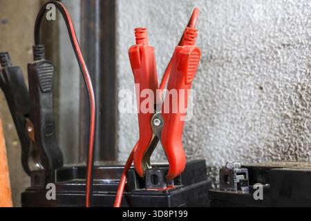 Pince positive rouge du câble de démarrage fixée à la borne de batterie du véhicule. EQUIPEMENT électrique utilisant l'énergie pour charger la batterie déchargée du véhicule pour l'entretien automatique Banque D'Images