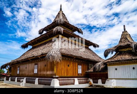 Bâtiment traditionnel en bois avec toit de chaume sous ciel bleu. Banque D'Images