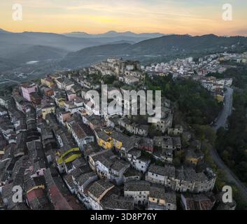 Vue aérienne d'une ville médiévale perchée de colline se prélasser dans la lueur chaude du soleil couchant, avec d'anciens bâtiments en pierre et des rues sinueuses, Calitri, Irpinia Banque D'Images