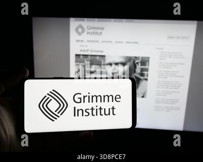 Dans cette illustration photo, une personne tient un smartphone avec le logo de l'organisation médiatique allemande Grimme-Institut sur l'écran devant le site Web. Banque D'Images