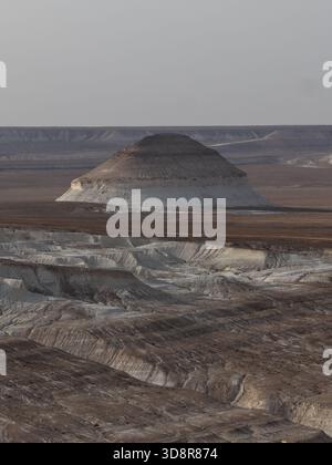 Paysage désertique aride révélant d'anciennes formations géologiques et des schémas d'érosion uniques sur un vaste terrain accidenté sous un ciel couvert Banque D'Images