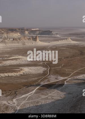 Vue aérienne par drone capturant des motifs abstraits de chemins de terre sinueux et de formations géologiques érodées à travers le vaste désert du paysage du canyon de Bozjyra Banque D'Images