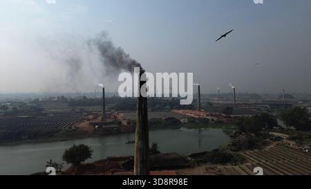 Dhaka, Bangladesh. 1er décembre 2025. De la fumée s'échappe des cheminées d'une usine de briques à la périphérie de Dhaka, au Bangladesh, le 2 décembre 2025. Ces usines de briques contribuent à la forte pollution atmosphérique au Bangladesh. L'indice de la qualité de l'air et de la vie (AQLI) classe le Bangladesh parmi les pays les plus pollués au monde. Selon l’Organisation mondiale de la santé (OMS), la pollution atmosphérique est responsable de la mort d’environ sept millions de personnes dans le monde chaque année, le 02 décembre. 2025, photo de Habibur Rahman/ABACAPRESS.COM crédit : Abaca Press/Alamy Live News Banque D'Images