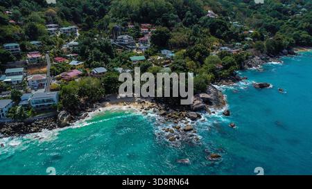 Crique isolée et littoral immaculé avec villas de vacances nichées au milieu de la végétation verte Banque D'Images