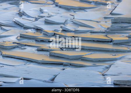 Vue de fragments de glace scintillants, dispersés comme des bijoux fracturés, reflétant une lueur chaude du coucher de soleil sur les eaux glacées de Jokulsarlon, Sveitarfelagid H. Banque D'Images