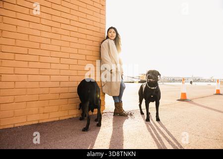 Femme et ses deux fidèles chiens noirs debout profitant du plein air urbain Banque D'Images