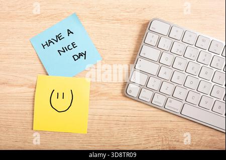 Note de motivation manuscrite et visage souriant sur des notes adhésives colorées dans l'espace de travail moderne, productivité et thème d'encouragement. Banque D'Images