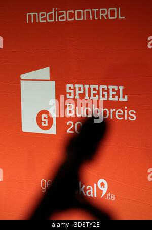 20 novembre 2025, Hambourg : L'ombre d'un microphone devant une cloison de séparation lors de la cérémonie de remise des prix du Spiegel Book Prize dans le foyer de la maison d'édition de Hambourg. Photo : Christian Charisius/dpa Banque D'Images