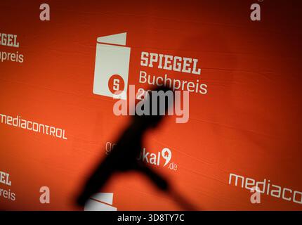 20 novembre 2025, Hambourg : L'ombre d'un microphone devant une cloison de séparation lors de la cérémonie de remise des prix du Spiegel Book Prize dans le foyer de la maison d'édition de Hambourg. Photo : Christian Charisius/dpa Banque D'Images
