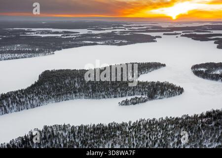 Vue aérienne au-dessus de la forêt et de la neige couverte de lac Lahnaselkä gelé à Kuusamo en hiver, Koillismaa, région de l'Ostrobothnie du Nord, Finlande, Scandinavie Banque D'Images
