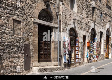 Assise, Italie - 12 juin 2025 : typique rue médiévale étroite assise avec façades en pierre et petites boutiques de cadeaux. Volets en bois Banque D'Images