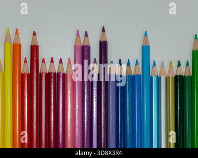 Captivant, gros plan, plan horizontal mettant en vedette une collection vibrante de crayons de couleur disposés dans un gradient arc-en-ciel dynamique sur un blanc épuré Banque D'Images
