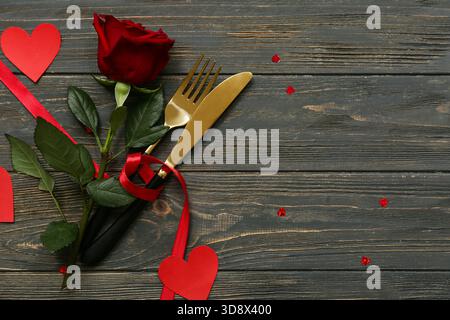 Table pour la Saint-Valentin avec coeurs en papier, ruban rouge et rose sur fond de bois noir Banque D'Images