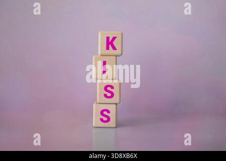 Le mot KISS est formé de blocs de bois sur un tissu bleu. Libérer de l'espace pour écrire. Banque D'Images