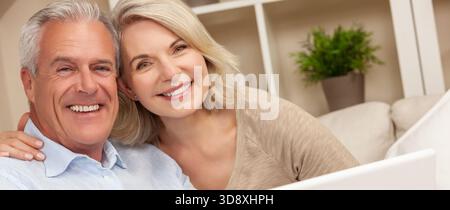 Heureux homme senior et femme couple ensemble à la maison souriant, sain et heureux à l'aide d'un ordinateur portable ou tablette Banque D'Images