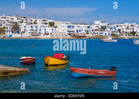 Ano Koufonisi, GR - 9 septembre 2025 : plusieurs bateaux colorés sont ancrés dans la mer avec les maisons blanches traditionnelles du village visibles sur le rivage Banque D'Images