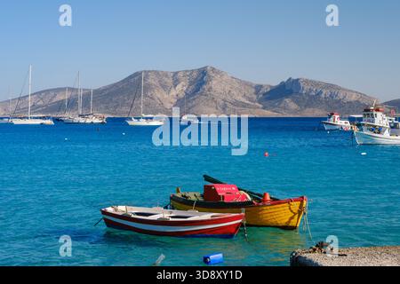 Ano Koufonisi, GR - 9 septembre 2025 : plusieurs bateaux colorés sont ancrés dans la mer avec l'île inhabitée de Keros visible en arrière-plan Banque D'Images